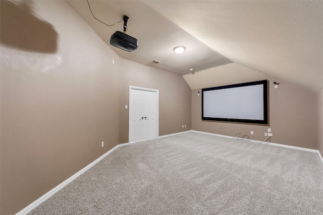 957 Pheasant Dr, Allen, TX 75013 - home theater featuring carpet floors, vaulted ceiling, and a textured ceiling