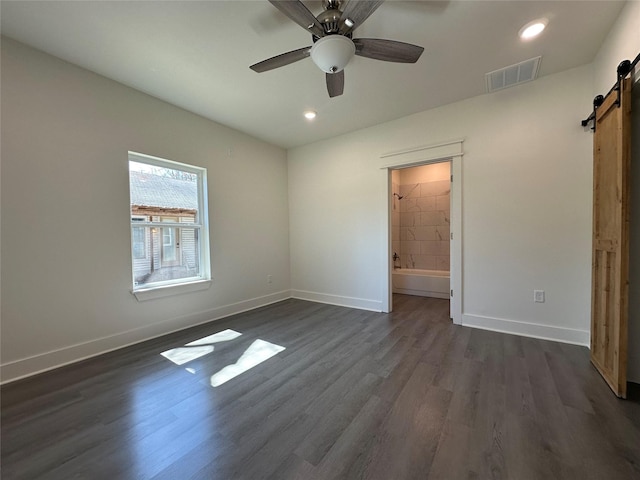 907 Davis St S, Sulphur Springs, TX 75482 - unfurnished bedroom with a barn door, baseboards, dark wood-style floors, recessed lighting, and ensuite bathroom