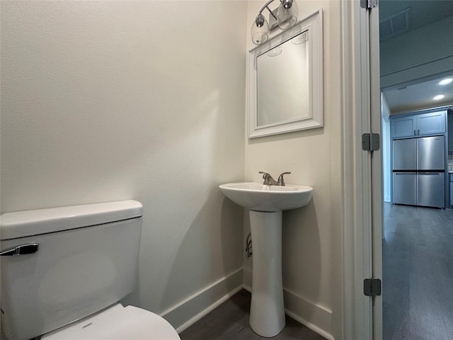 907 Davis St S, Sulphur Springs, TX 75482 - half bath featuring baseboards, toilet, wood finished floors, and a sink