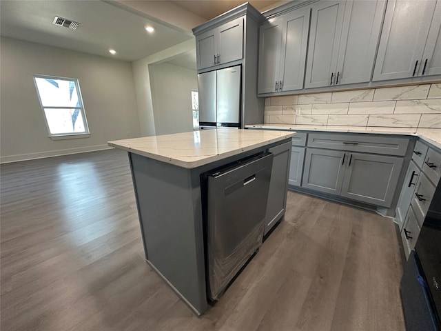 907 Davis St S, Sulphur Springs, TX 75482 - kitchen with gray cabinets, appliances with stainless steel finishes, dark wood-style flooring, a center island, and decorative backsplash