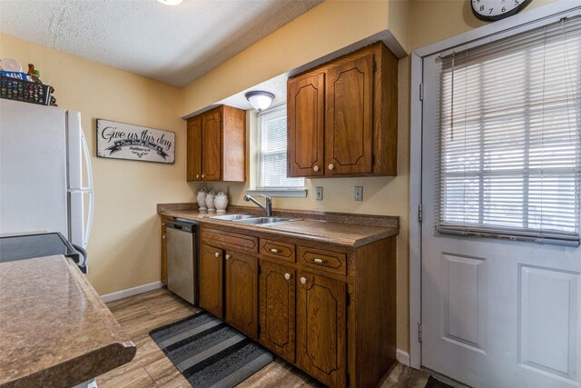 416 S 1st St, Wylie, TX 75098 - kitchen featuring a sink, stainless steel appliances, baseboards, brown cabinets, and a textured ceiling