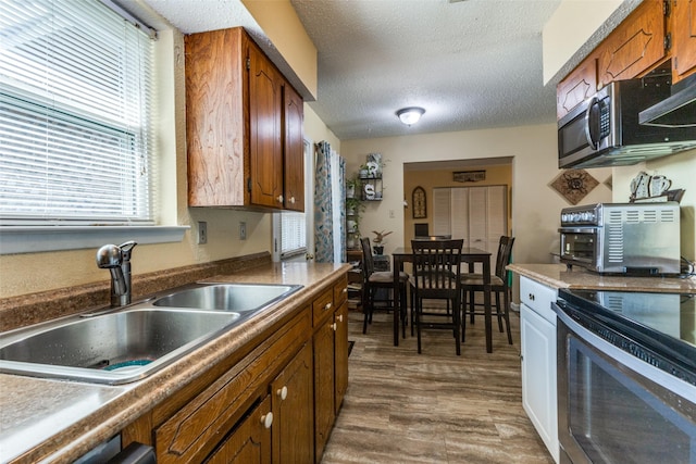 416 S 1st St, Wylie, TX 75098 - kitchen with a sink, range, stainless steel microwave, brown cabinets, and a textured ceiling