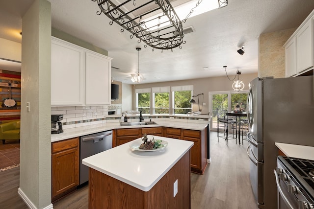 5033 Glenscape Trl, Fort Worth, TX 76137 - kitchen featuring appliances with stainless steel finishes, a sink, a peninsula, a center island, and wood finished floors