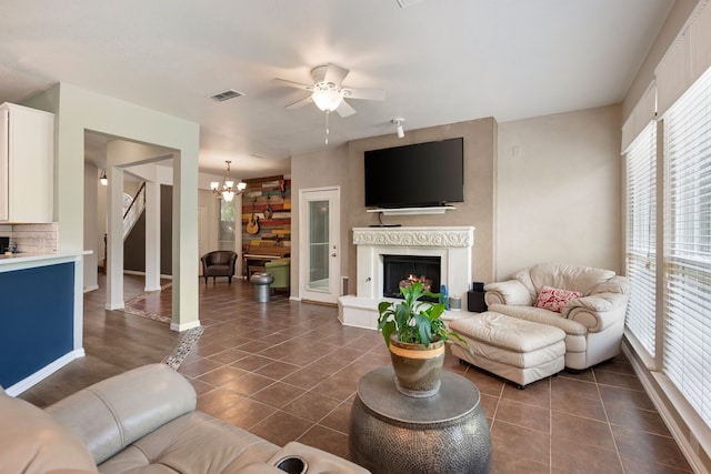 5033 Glenscape Trl, Fort Worth, TX 76137 - living room with a chandelier, ceiling fan, dark tile patterned flooring, and a warm lit fireplace