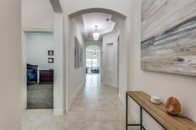 15616 Rockingham St, Frisco, TX 75036 - hallway with arched walkways, baseboards, light tile patterned floors, and a tray ceiling