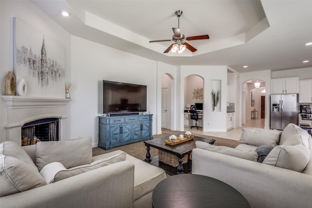 15616 Rockingham St, Frisco, TX 75036 - living room featuring arched walkways, ceiling fan, a raised ceiling, recessed lighting, and a fireplace