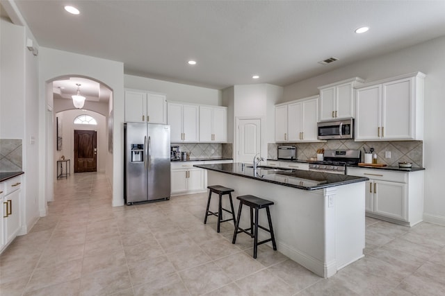 15616 Rockingham St, Frisco, TX 75036 - kitchen featuring appliances with stainless steel finishes, arched walkways, backsplash, recessed lighting, and white cabinets