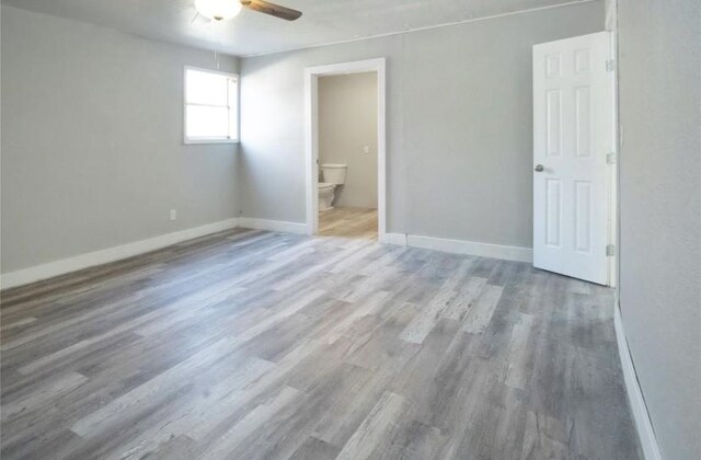 503 SW 15th Ave, Mineral Wells, TX 76067 - unfurnished bedroom with wood finished floors, baseboards, connected bathroom, and ceiling fan