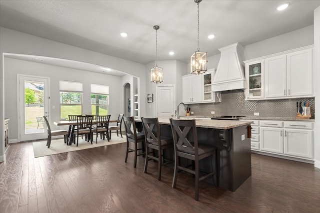 309 Bluffside Trl, Benbrook, TX 76126 - kitchen with premium range hood, a kitchen island with sink, a chandelier, dark wood-type flooring, and white cabinetry