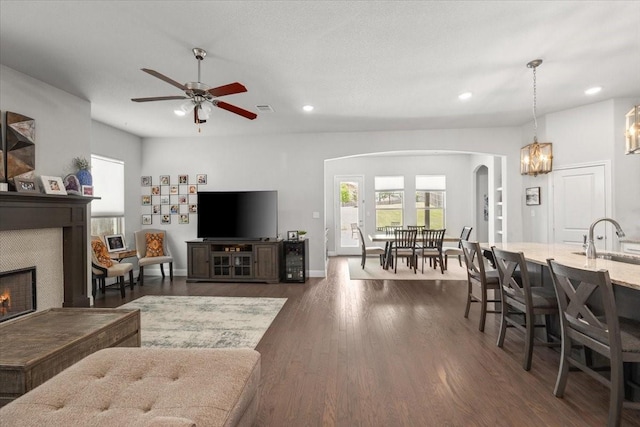 309 Bluffside Trl, Benbrook, TX 76126 - living area with arched walkways, a tiled fireplace, recessed lighting, dark wood finished floors, and ceiling fan