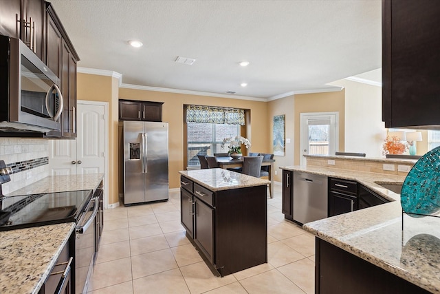 200 Baldwin Dr, Fate, TX 75189 - kitchen featuring stainless steel appliances, ornamental molding, decorative backsplash, light stone counters, and dark brown cabinetry