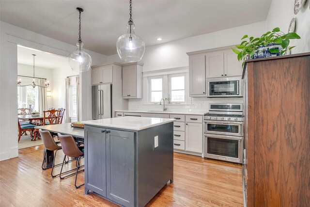 2913 Willing Ave, Fort Worth, TX 76110 - kitchen with appliances with stainless steel finishes, a sink, a center island, a kitchen bar, and light wood-type flooring