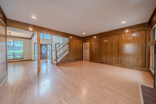 4404 Bentley Dr, Plano, TX 75093 - unfurnished room featuring a textured ceiling, light wood finished floors, stairs, wooden walls, and crown molding