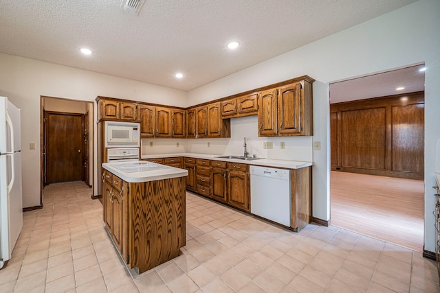 4404 Bentley Dr, Plano, TX 75093 - kitchen featuring white appliances, a sink, a kitchen island, light countertops, and a textured ceiling