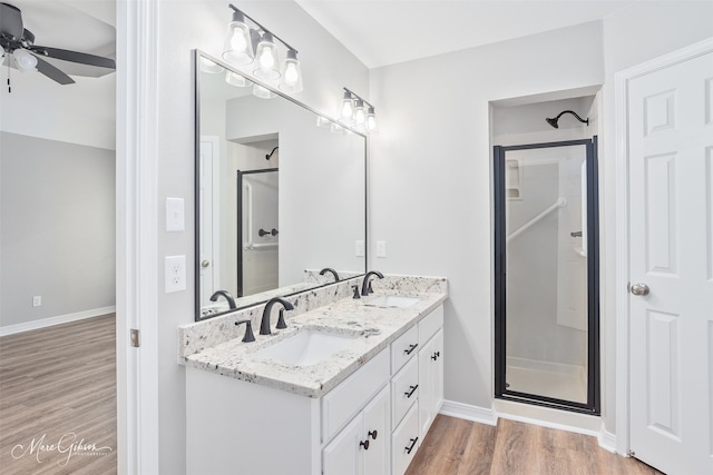 9756 Amblewood Ln, Shreveport, LA 71118 - full bathroom with wood finished floors, a shower stall, a ceiling fan, double vanity, and baseboards