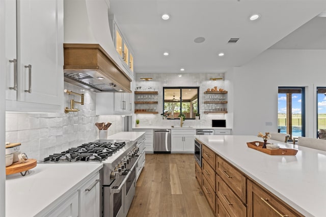 7799 Barber Ranch Rd, Fort Worth, TX 76126 - kitchen with stainless steel appliances, premium range hood, open shelves, white cabinets, and light wood-style flooring