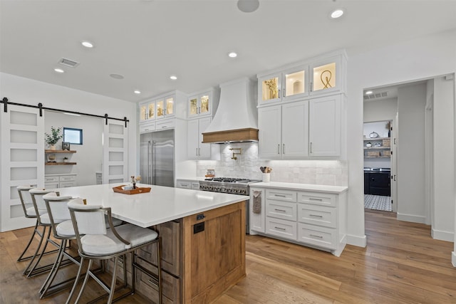 7799 Barber Ranch Rd, Fort Worth, TX 76126 - kitchen featuring custom exhaust hood, high end appliances, a barn door, a center island, and decorative backsplash