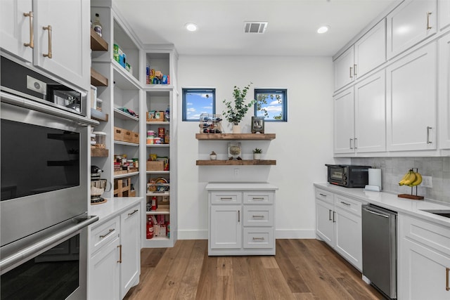 7799 Barber Ranch Rd, Fort Worth, TX 76126 - kitchen with open shelves, stainless steel double oven, light countertops, wood finished floors, and white cabinets