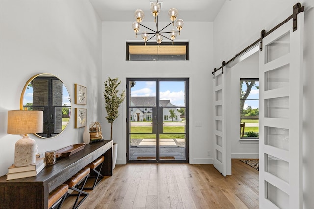 7799 Barber Ranch Rd, Fort Worth, TX 76126 - entrance foyer featuring a barn door, a chandelier, a towering ceiling, light wood-style floors, and french doors