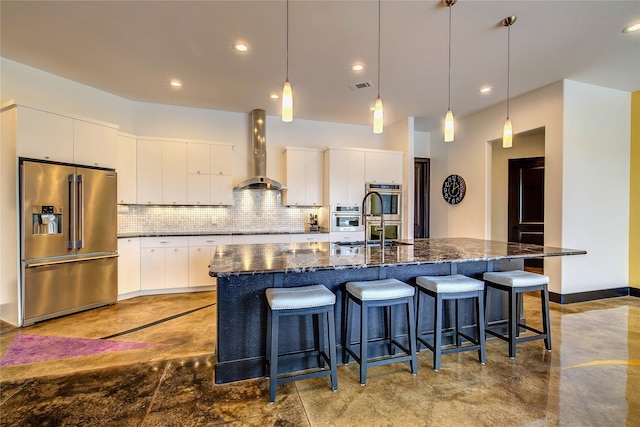 18133 Grandview Dr, Forney, TX 75126 - kitchen featuring appliances with stainless steel finishes, wall chimney exhaust hood, decorative backsplash, finished concrete flooring, and a kitchen island with sink