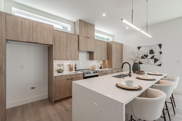 5320 Reiger Ave Unit 101, Dallas, TX 75214 - kitchen featuring stainless steel electric range, a sink, a breakfast bar, light wood-style floors, and light countertops