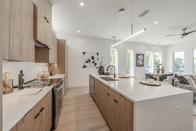 5320 Reiger Ave Unit 101, Dallas, TX 75214 - kitchen with a sink, modern cabinets, stainless steel appliances, light wood-style floors, and a kitchen island with sink