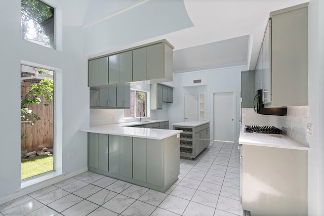 8907 Club Creek Cir, Dallas, TX 75238 - kitchen featuring gray cabinetry, light marble finish flooring, a peninsula, backsplash, and healthy amount of natural light