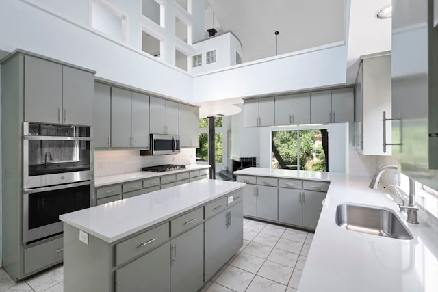 8907 Club Creek Cir, Dallas, TX 75238 - kitchen with gray cabinetry, stainless steel appliances, light marble finish floors, a kitchen island, and a high ceiling