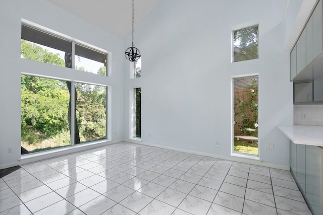8907 Club Creek Cir, Dallas, TX 75238 - unfurnished dining area with a high ceiling, plenty of natural light, light marble finish floors, and a chandelier