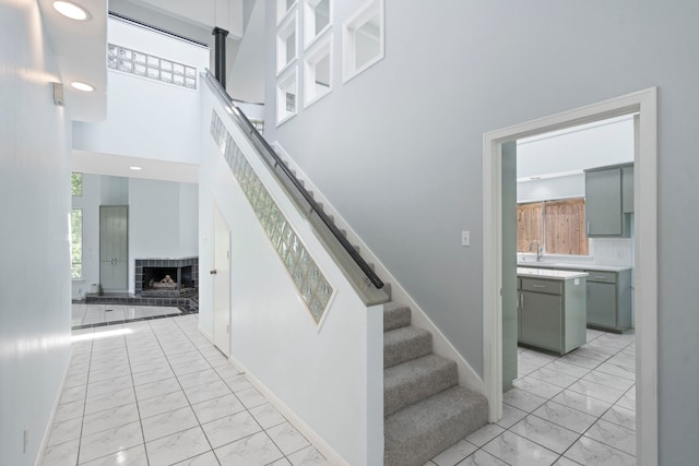 8907 Club Creek Cir, Dallas, TX 75238 - stairs with marble look tiles, a fireplace, a high ceiling, and recessed lighting