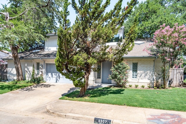 8907 Club Creek Cir, Dallas, TX 75238 - view of property hidden behind natural elements featuring concrete driveway, a front yard, brick siding, and a shingled roof