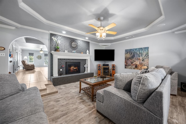 120 Hollie Dr, Red Oak, TX 75154 - living room with a raised ceiling, a ceiling fan, ornamental molding, a brick fireplace, and arched walkways