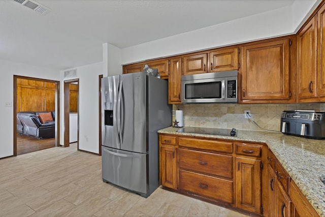 1614 Shadow Moss Way, Carrollton, TX 75007 - kitchen featuring stainless steel appliances, backsplash, brown cabinets, light stone counters, and light wood-type flooring