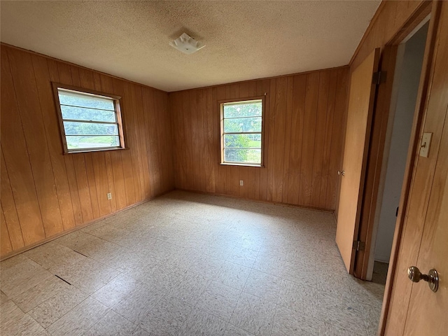 430 Cranford St, Sulphur Springs, TX 75482 - spare room with plenty of natural light, tile patterned floors, wood walls, and a textured ceiling