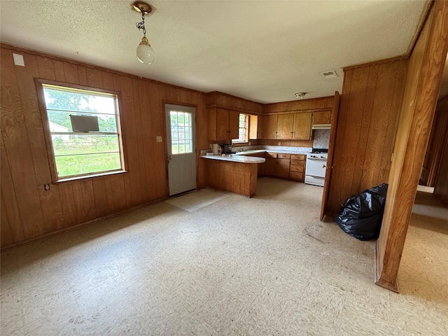 430 Cranford St, Sulphur Springs, TX 75482 - kitchen with brown cabinets, white gas range oven, a peninsula, a textured ceiling, and light countertops