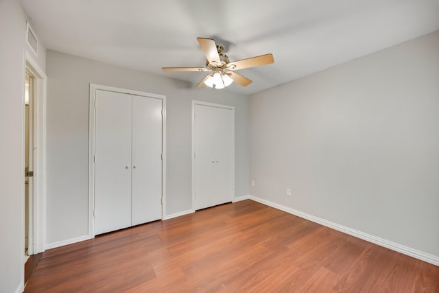 3121 Park Ln Unit 1103, Dallas, TX 75220 - unfurnished bedroom with wood finished floors, baseboards, ceiling fan, and multiple closets