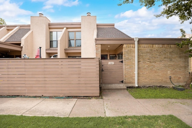 3121 Park Ln Unit 1103, Dallas, TX 75220 - exterior space featuring a fenced front yard, a chimney, a gate, brick siding, and stucco siding