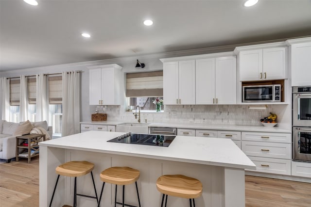 3916 Boulton Ct, Plano, TX 75025 - kitchen featuring a sink, appliances with stainless steel finishes, a kitchen bar, white cabinetry, and backsplash