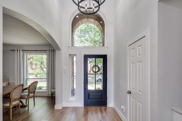 3916 Boulton Ct, Plano, TX 75025 - entrance foyer with a chandelier, arched walkways, light wood-type flooring, plenty of natural light, and a high ceiling