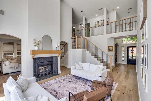 3916 Boulton Ct, Plano, TX 75025 - living room with a towering ceiling, stairway, arched walkways, a fireplace, and wood finished floors