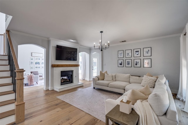 3916 Boulton Ct, Plano, TX 75025 - living room with arched walkways, ornamental molding, light wood-style floors, stairs, and a chandelier