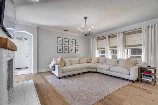 3916 Boulton Ct, Plano, TX 75025 - living room featuring a chandelier, light wood-type flooring, crown molding, a fireplace, and baseboards