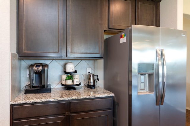 2400 Prairie Trail Ave, Aubrey, TX 76227 - kitchen featuring stainless steel fridge with ice dispenser, dark brown cabinets, decorative backsplash, and light stone countertops