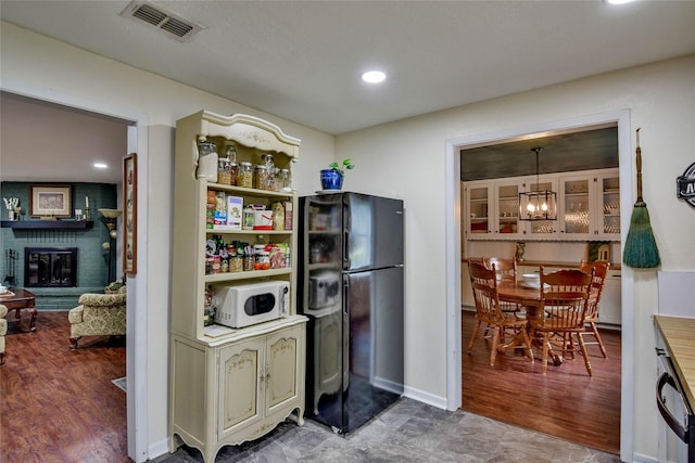 366 W Blackjack St, Dublin, TX 76446 - kitchen with freestanding refrigerator, white microwave, a chandelier, a brick fireplace, and wood finished floors