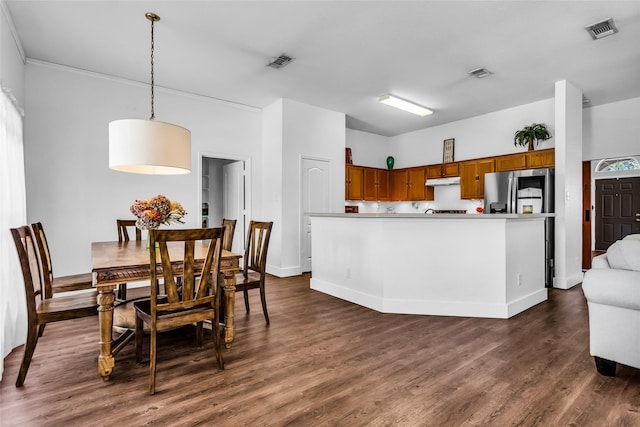 432 Maplegrove Rd, Cedar Hill, TX 75104 - kitchen featuring brown cabinets, under cabinet range hood, dark wood-style flooring, decorative light fixtures, and light countertops