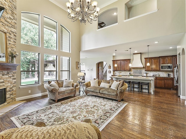 701 Buffalo Springs Dr, Prosper, TX 75078 - living area featuring arched walkways, dark wood-type flooring, a high ceiling, a stone fireplace, and a chandelier