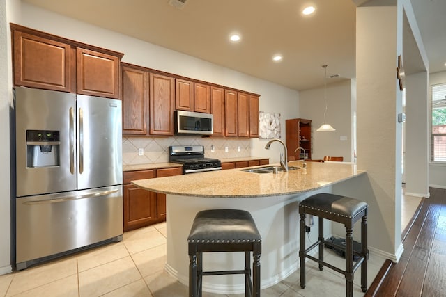 10520 Sexton Dr, Mckinney, TX 75072 - kitchen featuring stainless steel appliances, a sink, a breakfast bar area, decorative backsplash, and light stone countertops