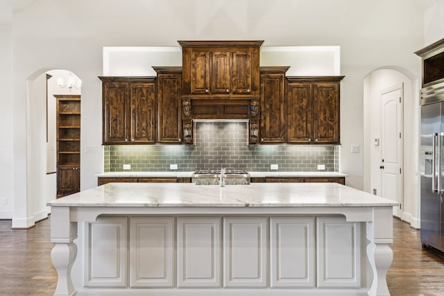 3708 Ledgestone Ct, Richardson, TX 75082 - kitchen with built in fridge, arched walkways, dark wood finished floors, and light stone counters