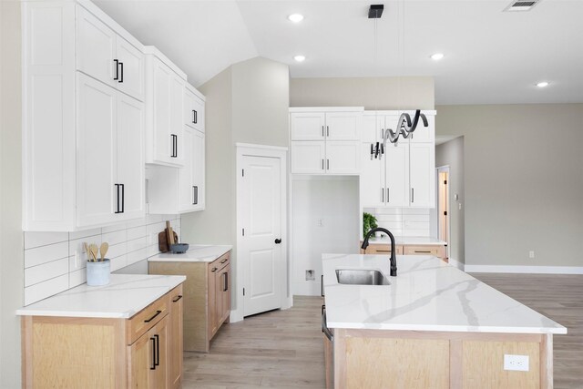 1621 S Chisholm Trl, Granbury, TX 76048 - kitchen featuring a sink, light wood-type flooring, light stone countertops, a center island with sink, and vaulted ceiling