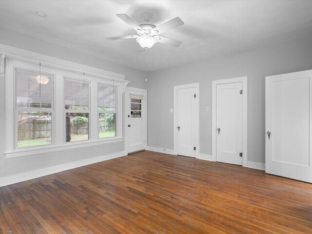 605 W Crockett St, Ennis, TX 75119 - unfurnished bedroom with baseboards, wood finished floors, and two closets